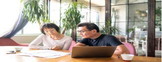 Couple at table with laptop looking at a printed plan